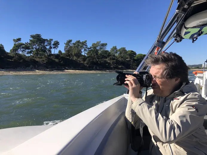 Person photographing landscape from a boat on a sunny day.