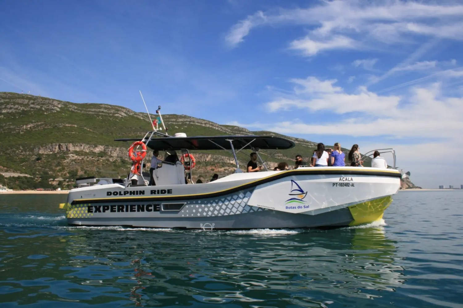 Tour boat named 'Experience' on water with people aboard, distant hills in background.