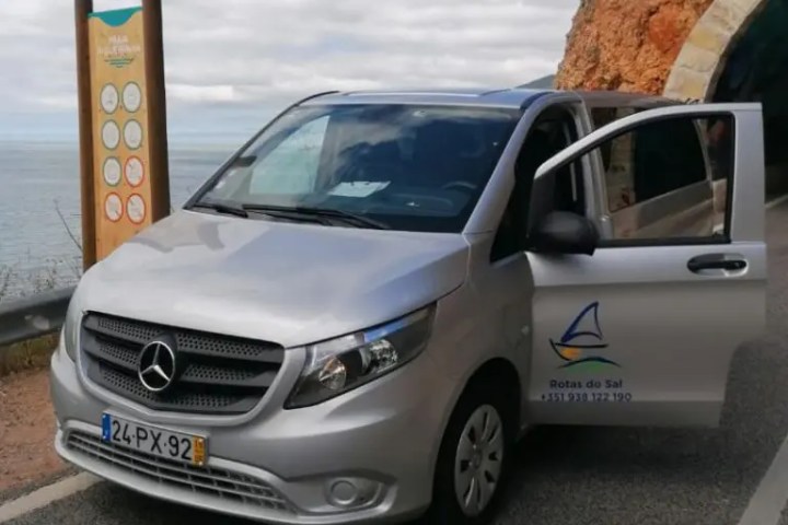 Silver van parked near coastal road with tunnel entrance in the background.