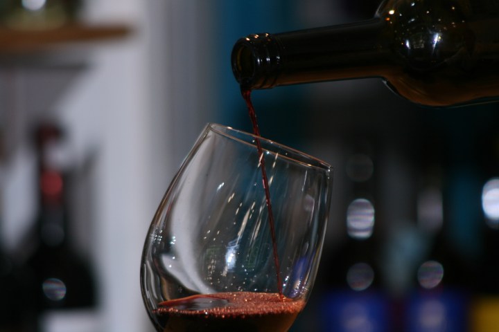 Red wine being poured into a tilted clear glass.