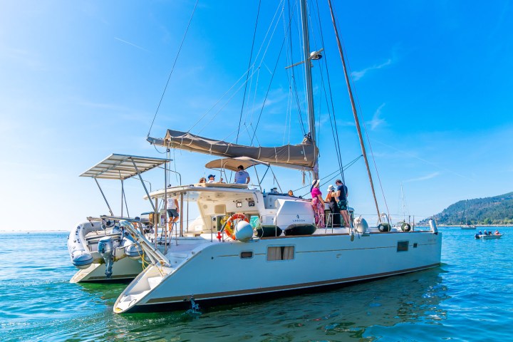 Catamaran with people enjoying the sunny day on calm blue sea.
