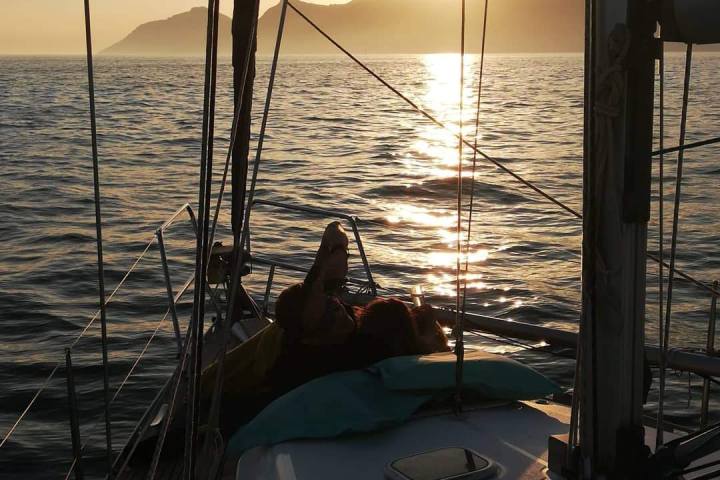Sunset view from sailboat with hills in distance.
