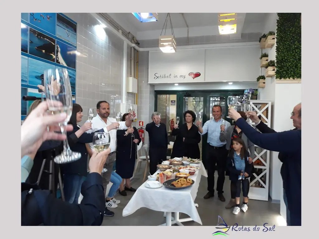 Group of people toasting with glasses in a room with food on a table.