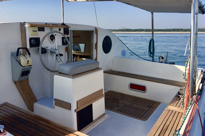 Open-deck boat with steering wheel, seating, and canopy on calm water.