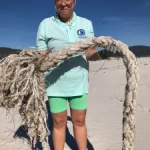 Person holding large rope on a sunny beach.