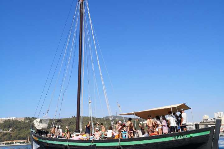 People on a wooden sailing boat under clear blue sky.