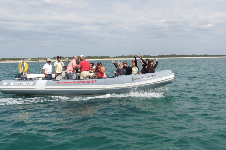 Group of people waving on a motorboat in calm sea waters.
