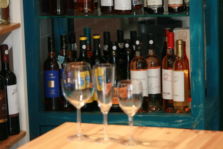 Empty wine glasses in front of wine bottles on wooden shelves.