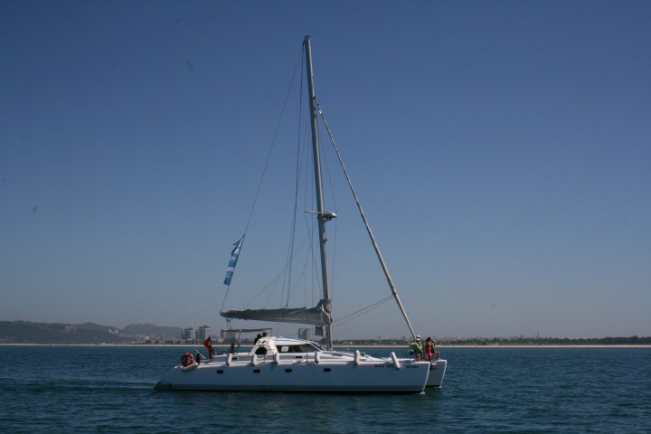 Catamaran sailing on calm water under clear blue sky.