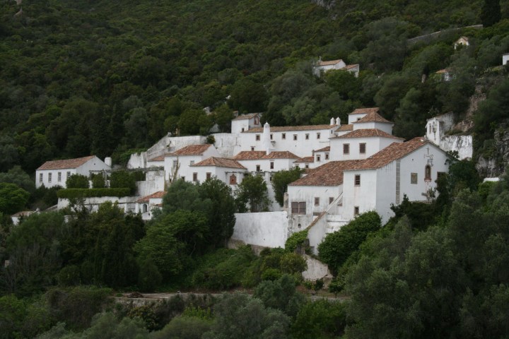 White hillside village with red-tiled roofs surrounded by lush greenery.