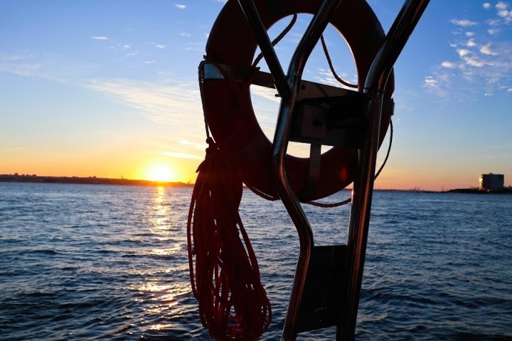 Lifebuoy on boat with sunset over calm sea in background.