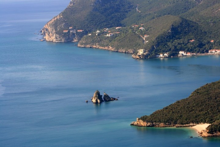 Coastal landscape with rocky islands and lush green hills.
