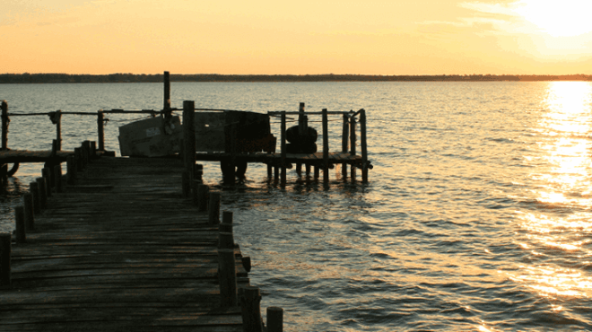 Sunset over a lake with a wooden dock extending into the water.