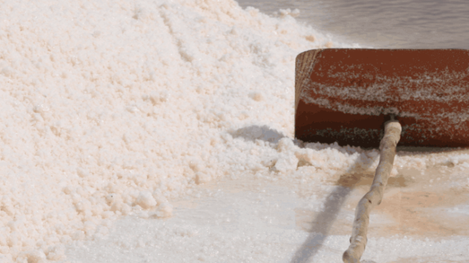 Rusty barrel and wooden post in a salt field pile.