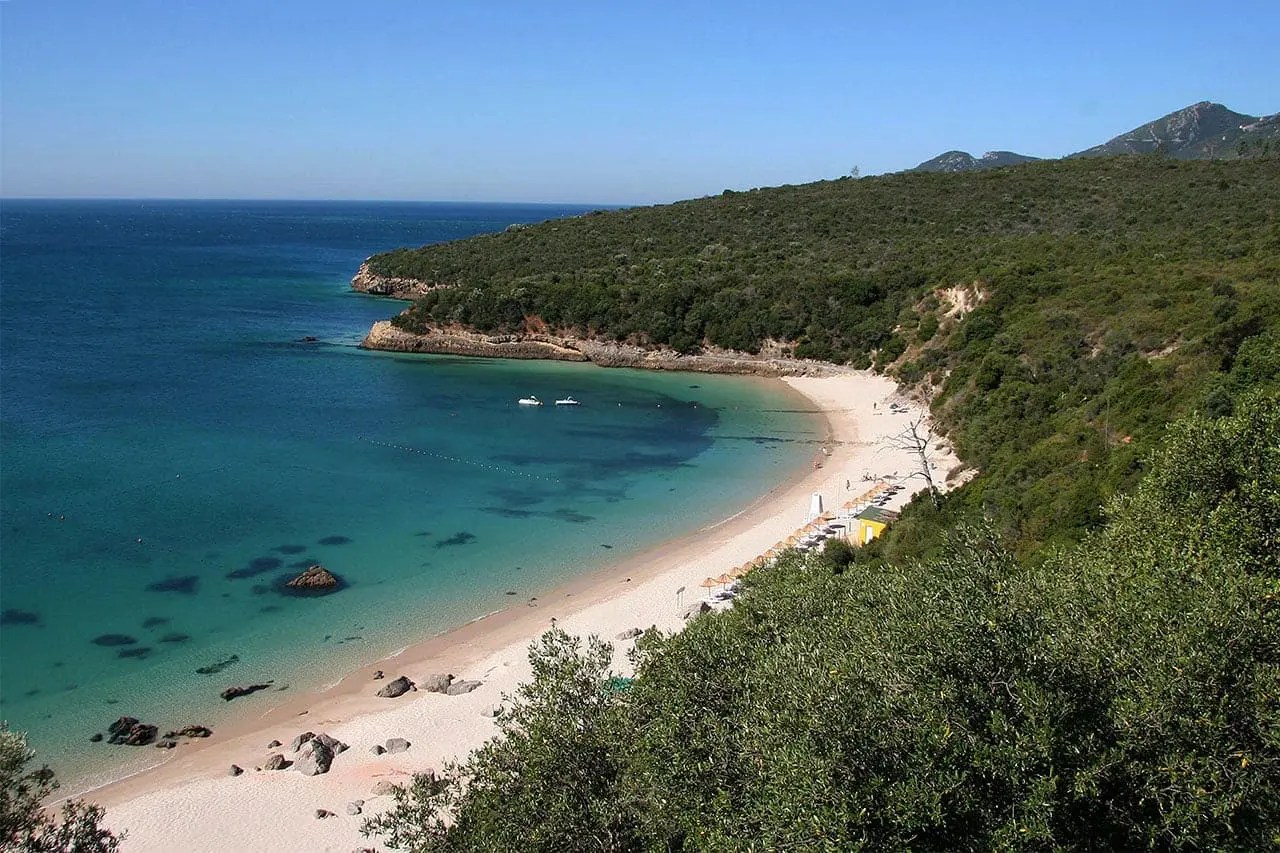 Secluded beach with clear blue water and lush green hills.
