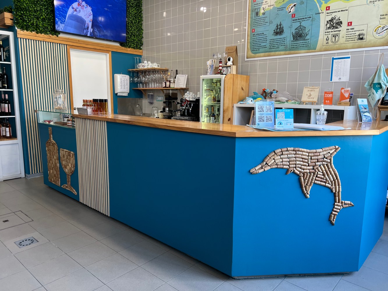 Blue counter with dolphin decor, wine bottle art, and a TV on the wall.