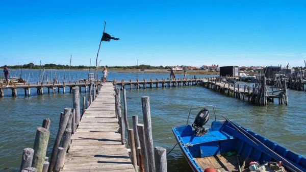 Wooden pier over water, blue boat, clear sky