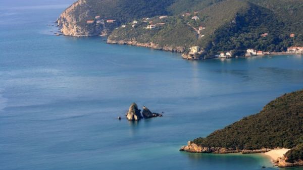 Coastal landscape with rugged cliffs and calm blue sea.